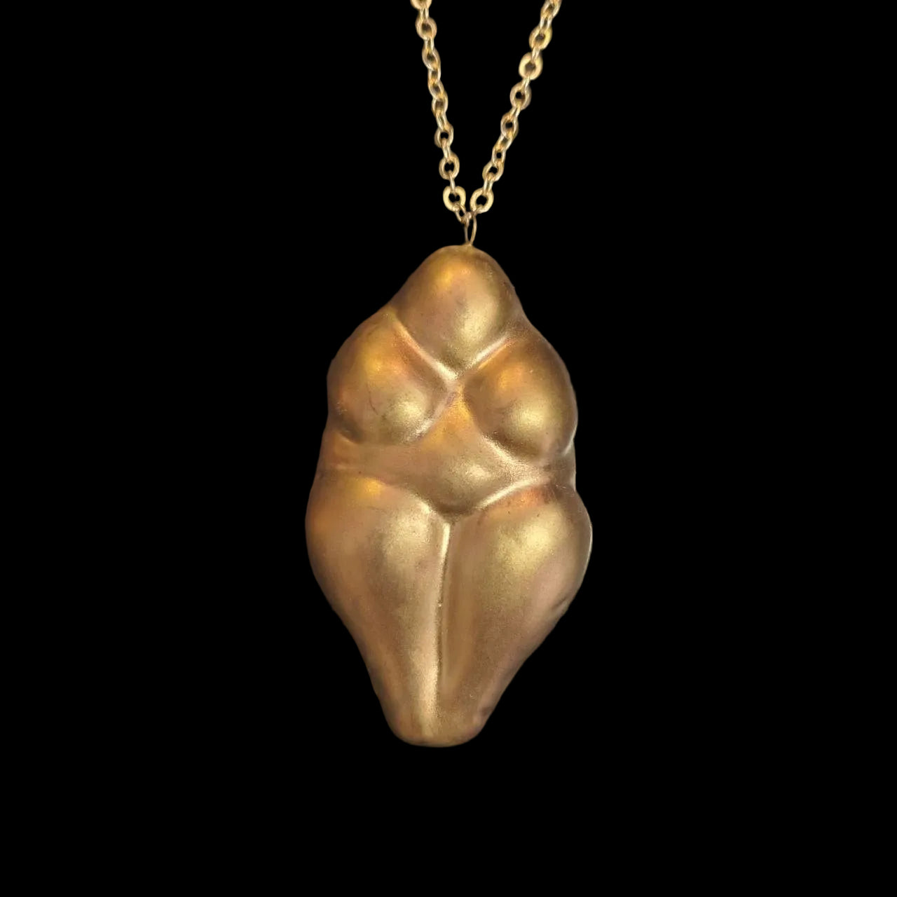 Gold pendant necklace ocarina on a textured black background