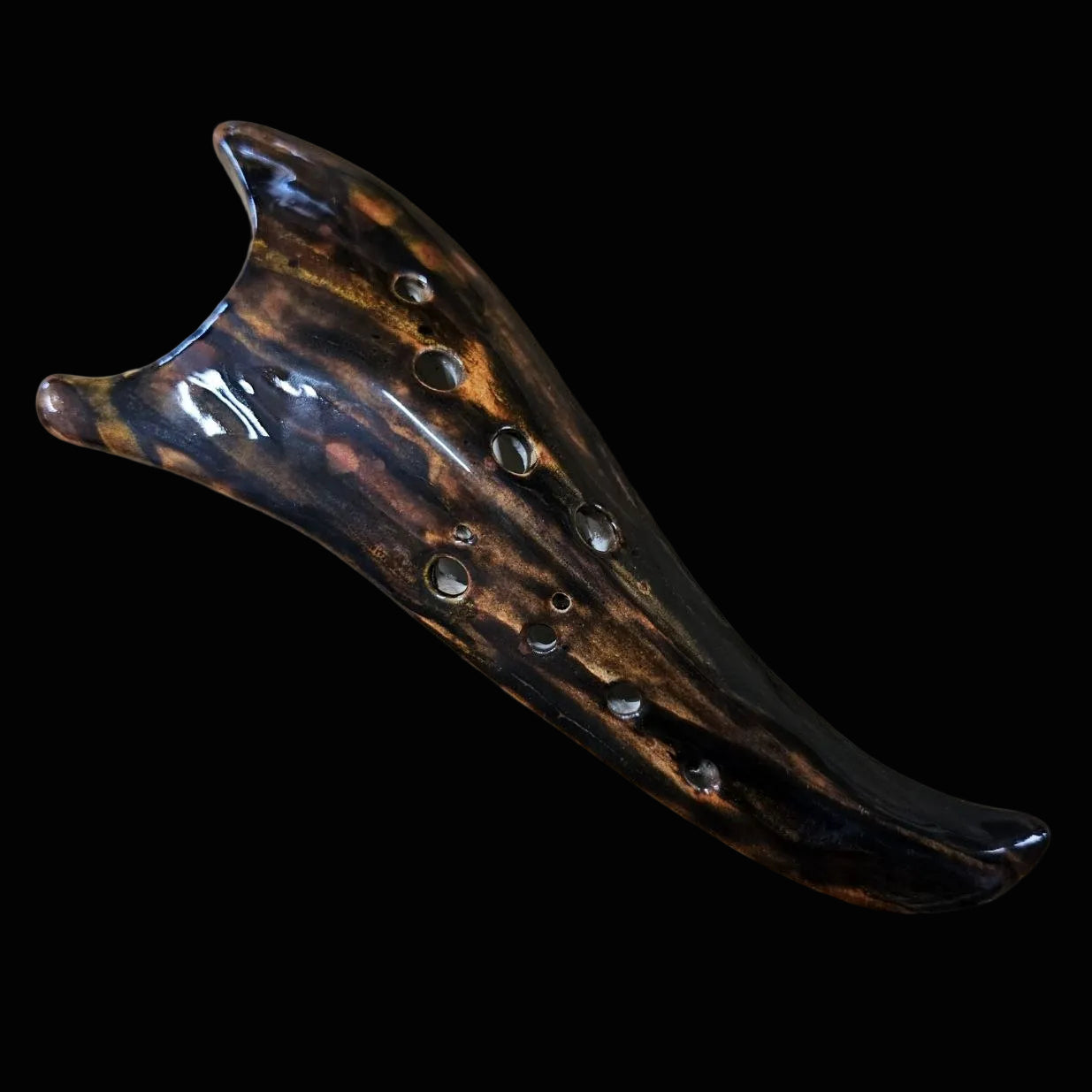 A handmade ceramic ocarina with a glossy dark brown and black marbled pattern
