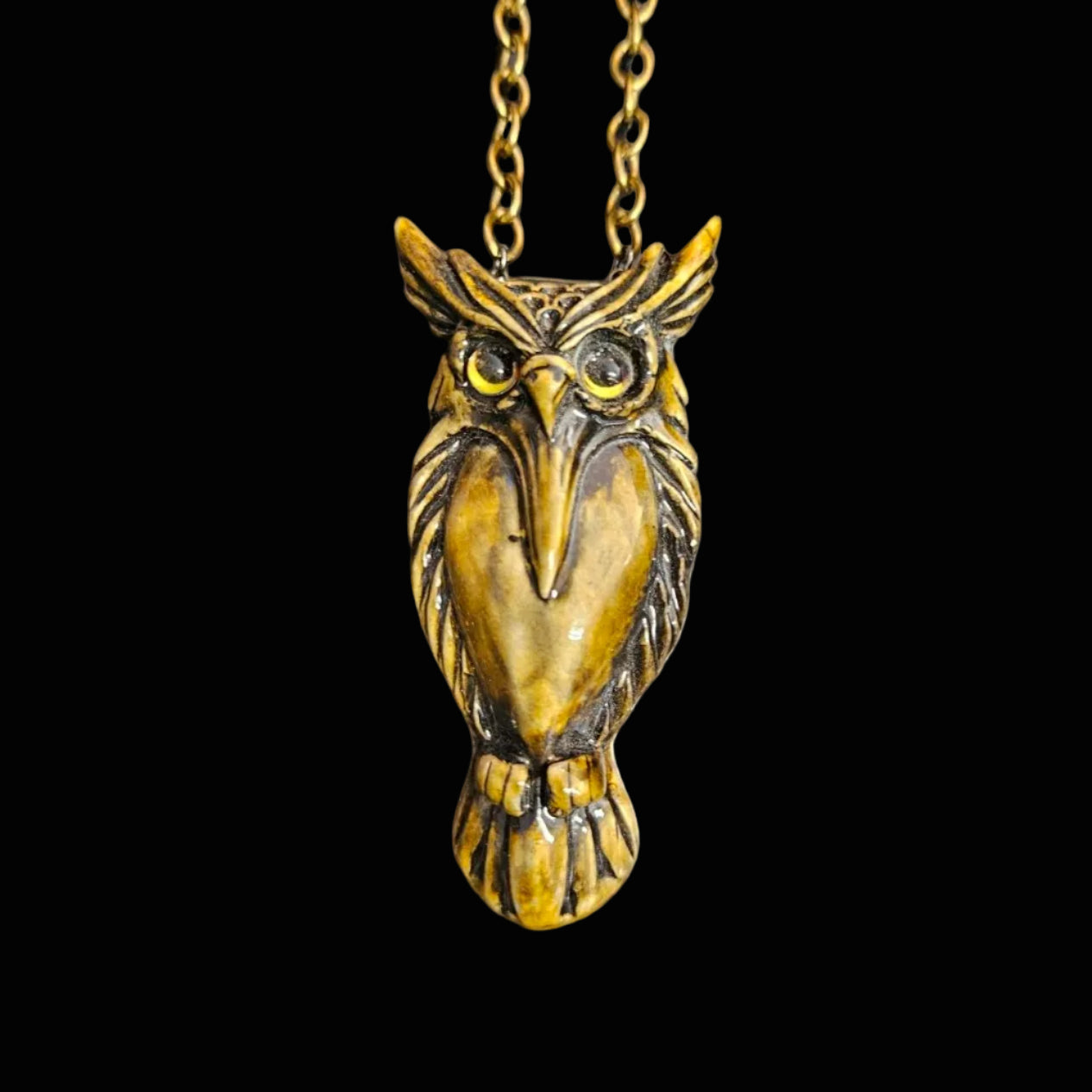 An antique bronze owl pendant necklace on a matching chain, displayed on a dark textured surface.