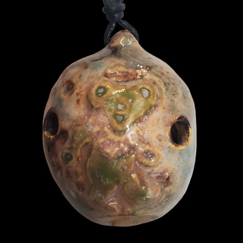 Ceramic pendant with green and brown glaze on a black cord with a dancing bear